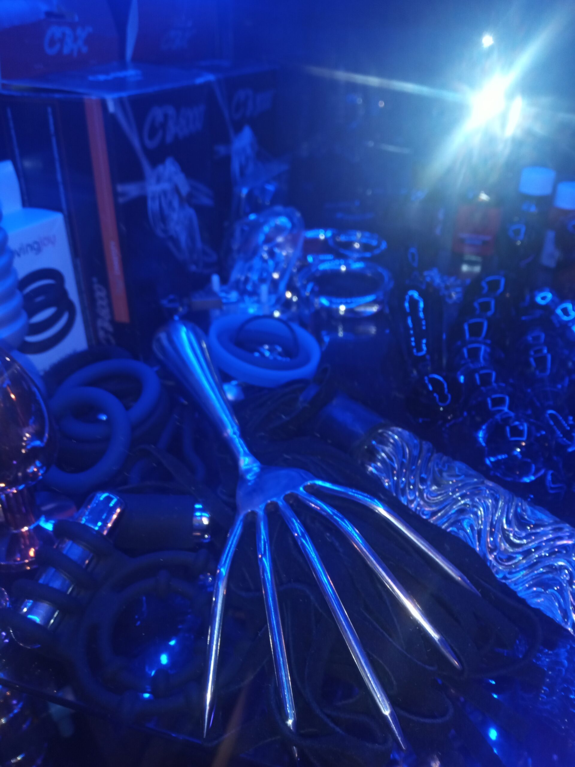 Devils claw, assorted cock rings, glass dildos & chastity devices displayed in a male pro-dom's toy cabinet